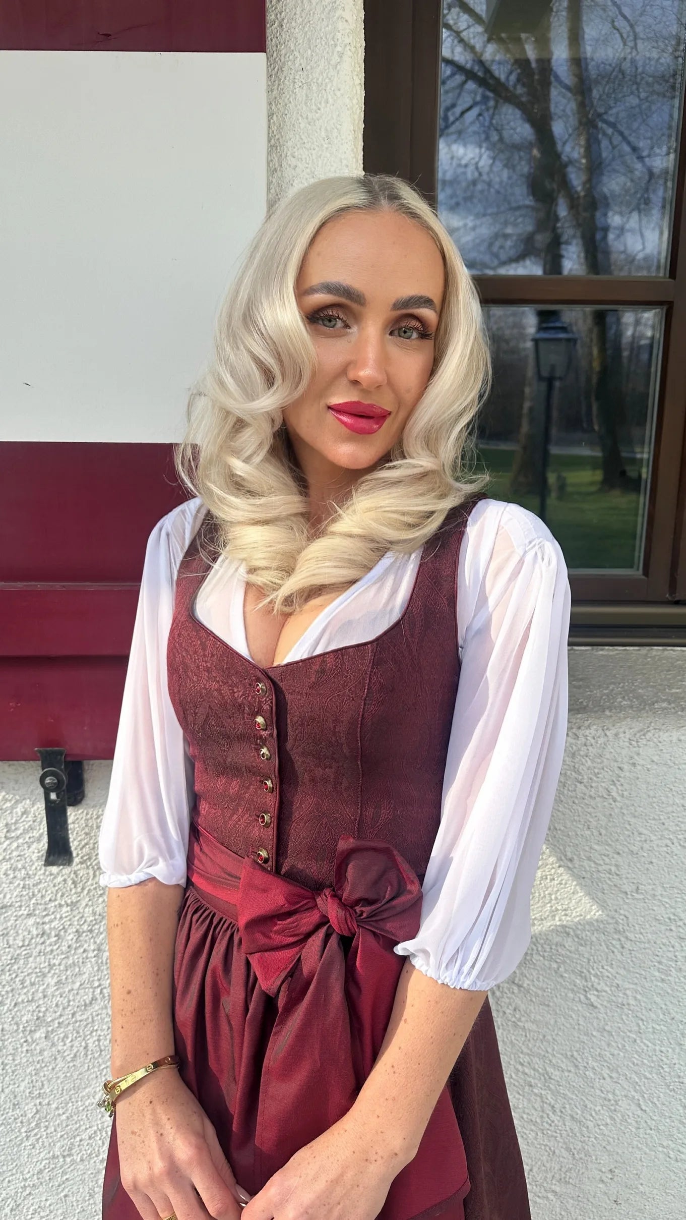 Zeigt das getragene rote Dirndl Sophie Rouge Edition und die weise Bluse Helene Blanche.