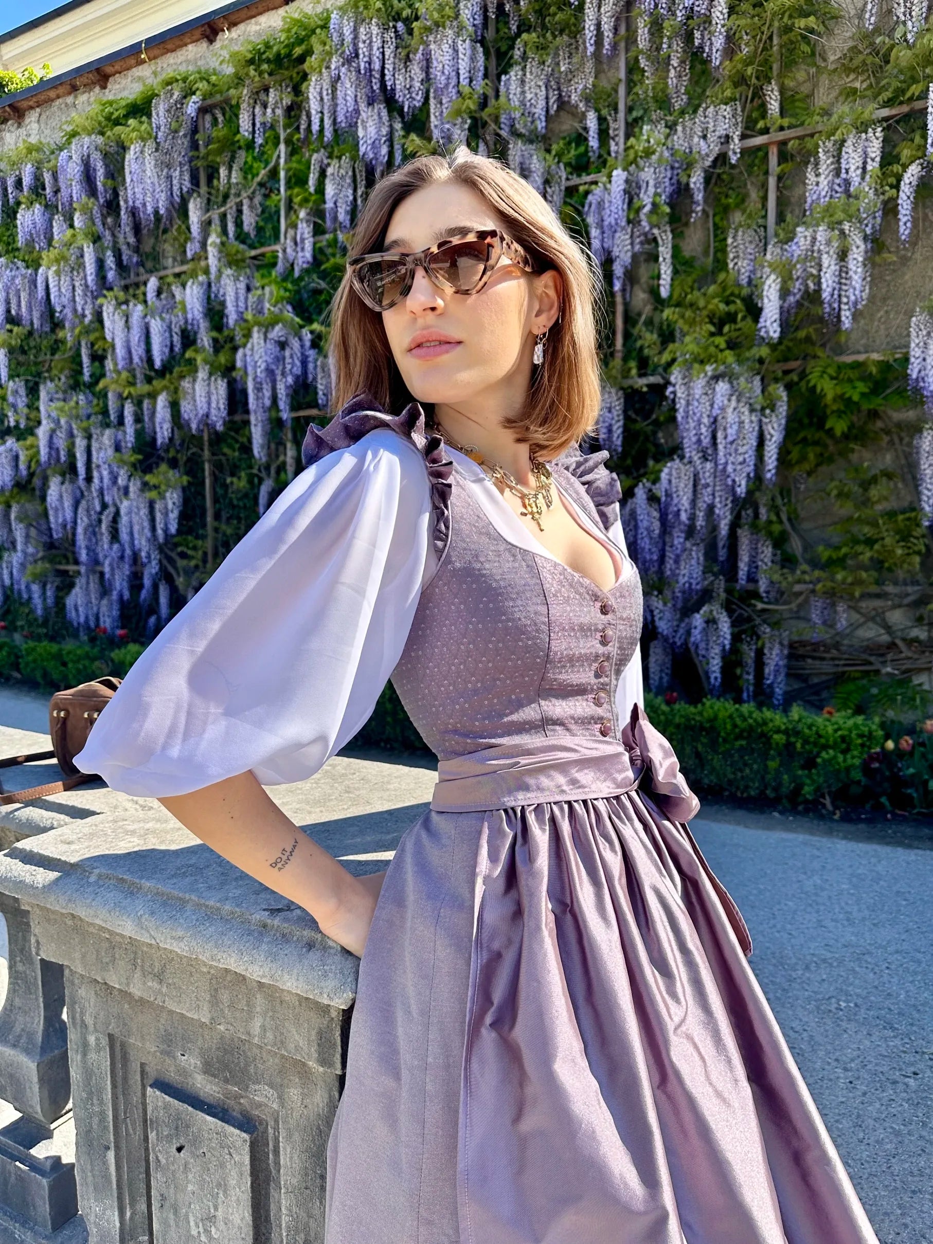 Zeigt das getragene lila Dirndl Sophie Lilac Legacy und die weise Bluse Helene Blanche.
